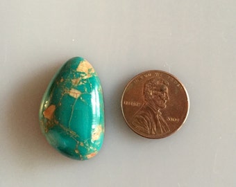 May include: A turquoise cabochon with brown matrix, measuring approximately the size of a US penny.