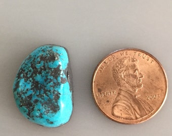 May include: A turquoise cabochon gemstone with a dark matrix, measuring approximately the size of a US penny.