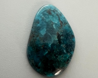 May include: A polished, teardrop-shaped gemstone with a vibrant mix of teal, turquoise, and deep blue hues. The stone has a glossy finish and displays natural patterns and variations in color, with some areas appearing nearly black.