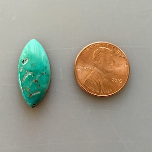 Könnte beinhalten: Ein türkisfarbener Cabochon-Edelstein in Marquise-Form, etwa so groß wie ein 1-Cent-Stück.
