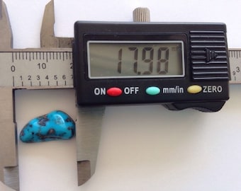 May include: A turquoise stone measuring 17.98 mm in a digital caliper.