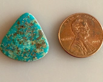 May include: A turquoise cabochon with a triangular shape and a mottled green and blue color. The stone is approximately the size of a US penny.