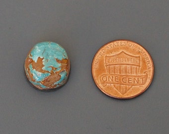 May include: A turquoise cabochon gemstone with brown matrix, measuring approximately the size of a US penny.