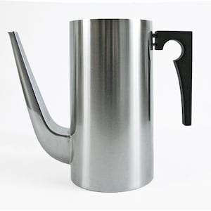 May include: A tall, stainless steel coffee pot with a long, curved spout and a black handle. The pot has a cylindrical body and a modern, minimalist design, perfect for brewing coffee.