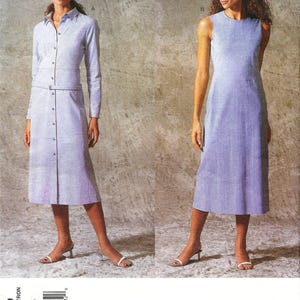 May include: A sewing pattern envelope for Calvin Klein Vogue American Designer pattern 2439, featuring two dress variations: a long-sleeved button-front collared dress with a belt and a sleeveless round-neck dress, both in a light blue checkered fabric.