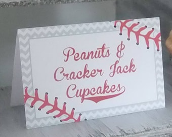 Könnte beinhalten: Ein mehrstufiger Holzständer mit Baseball-Cupcakes, die mit Erdnussbutter-Frosting verziert sind. Das Schild lautet "Peanuts & Cracker Jack Cupcakes".