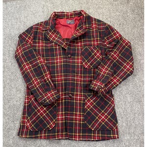 May include: A long-sleeve jacket featuring a dark navy blue, red, and yellow plaid pattern. The jacket has a collared neckline, a front button closure, one chest pocket, two lower patch pockets, and a solid red interior lining with a visible label.