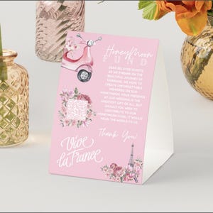 Puede incluir: Tarjeta de boda rosa y blanca con una ilustración de acuarela de un scooter, flores y la Torre Eiffel. La tarjeta dice "Fondo de luna de miel" y "Vive la France".