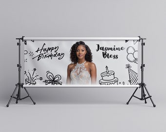 May include: White banner with black doodle drawings of a birthday cake, balloons, a party hat, a gift, and fireworks. The text "Happy Birthday" and "Jasmine Bless" are written in black cursive. A woman with curly black hair is pictured in the center of the banner.