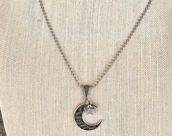 May include: Silver necklace featuring a crescent moon pendant inscribed with the words "I love you to the moon and back" and a small star charm.