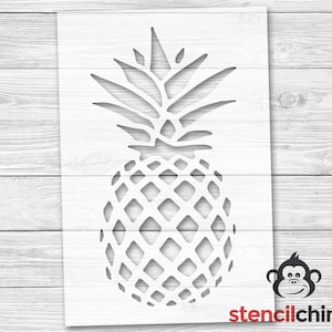 May include: A white stencil of a pineapple with a detailed design. The stencil is on a white wooden background. The stencil is for crafting and decorating.