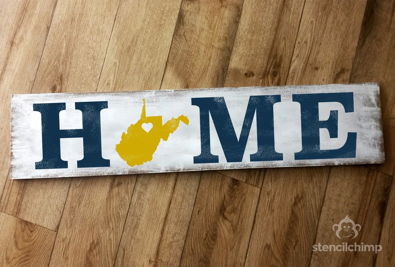 May include: A white wooden sign with the word "HOME" in blue letters. The state of West Virginia is painted in yellow with a small white heart in the center.