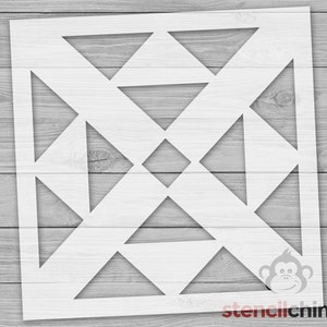 May include: A white stencil with a geometric design of overlapping triangles and a diamond shape in the center. The stencil is on a wood background.