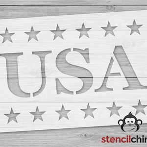 May include: A white stencil with the word "USA" in large letters and a row of stars above and below the word. The stencil is on a woodgrain background.