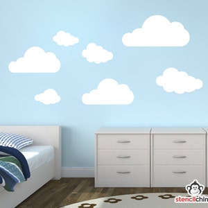 May include: White cloud wall decals on a light blue wall. The decals are arranged in a random pattern and are of varying sizes. There are two white dressers with silver drawer pulls in the bottom of the image.