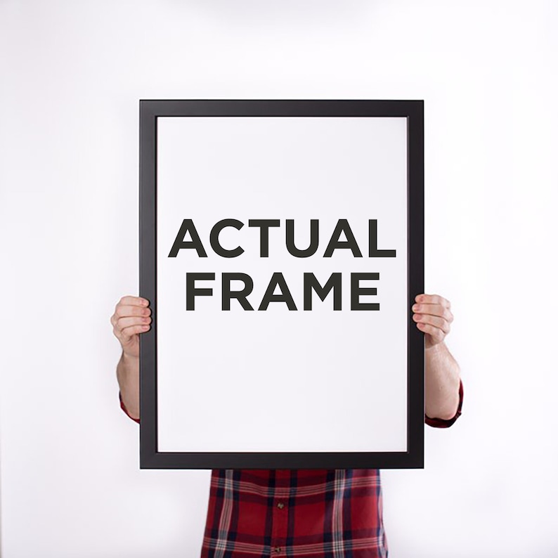 May include: A black rectangular frame with the words "ACTUAL FRAME" in bold, black letters on a white background. The frame is held up by a person wearing a red and black plaid shirt.