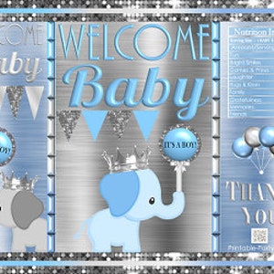 May include: Blue and gray baby shower favor bags with a silver glitter background. The bags feature an elephant with a crown holding a lollipop that says "It's a Boy!" The bags also have the text "Welcome Baby" and "Thank You".