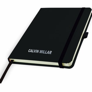 May include: Black notebook with a black elastic band closure and a silver inscription that reads "CALVIN MILLAR".