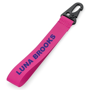 May include: Pink key chain with a black clip and the text "LUNA BROOKS" in navy blue.