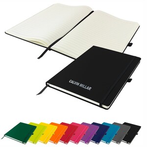 May include: A black hardcover notebook with a black elastic closure and a black ribbon bookmark. The notebook has the text "CALVIN MILLAR" printed in silver on the front cover. The notebook is open to reveal lined pages. A row of notebooks in various colors is shown below the main notebook.