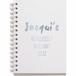 May include: A white spiral bound notebook with the text "Jacqui's Ridiculously Brilliant Ideas" in silver lettering.