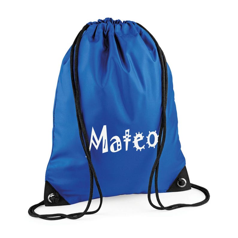 May include: A royal blue drawstring backpack with black drawstrings and corner reinforcements. The name "Mateo" is printed in white, with the letter "o" replaced by a gear design. The bag is made of a smooth, durable material.