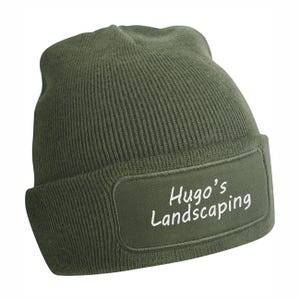 Può includere: Berretto verde oliva con toppa rettangolare. La toppa mostra il testo "Hugo's Landscaping" in bianco. Il berretto è realizzato in tessuto a maglia a coste.