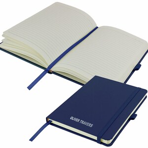 May include: A navy blue notebook with a matching ribbon bookmark. The notebook has a lined interior and a silver embossed inscription that reads "OLIVER TRAVERS".