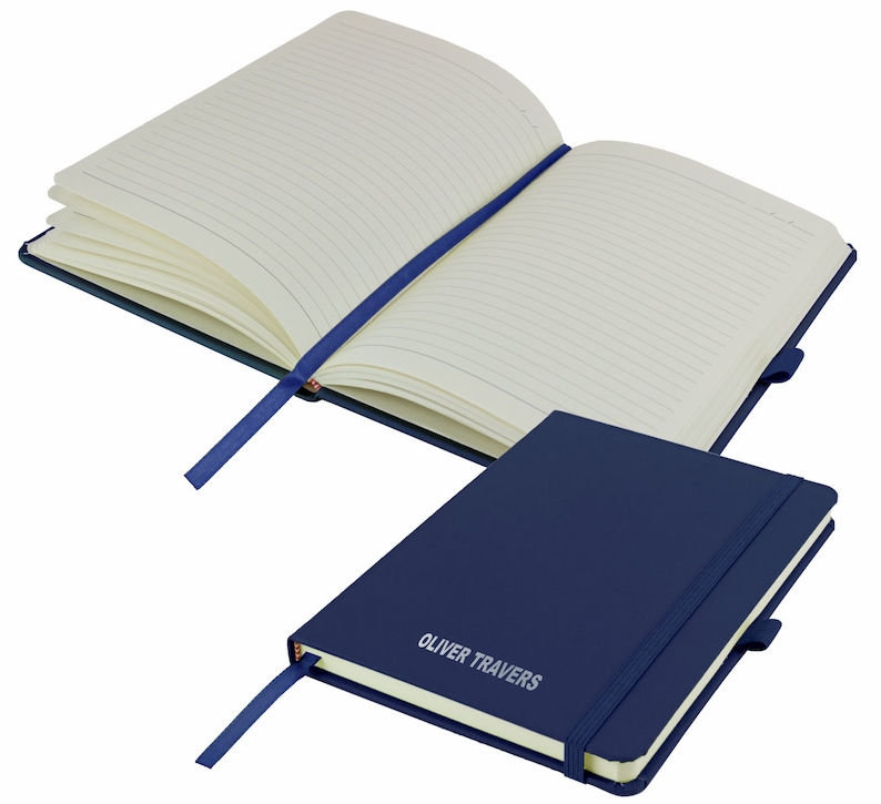 May include: A navy blue notebook with a matching ribbon bookmark. The notebook has a lined interior and a silver embossed inscription that reads "OLIVER TRAVERS".