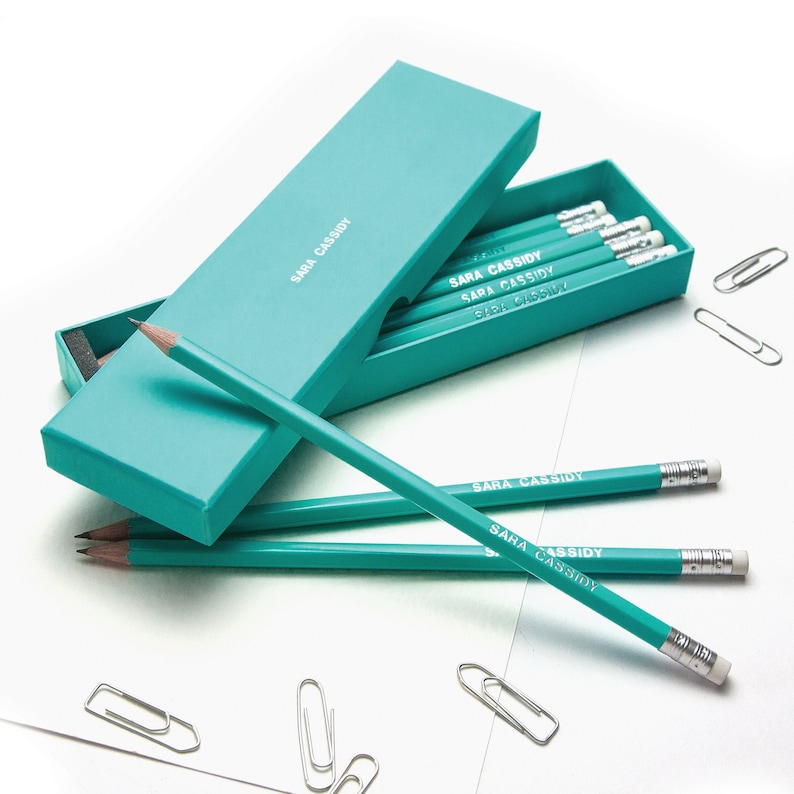May include: A set of teal pencils with the name "SARA CASSIDY" printed on each pencil. The pencils are in a teal box with the same name printed on the box.