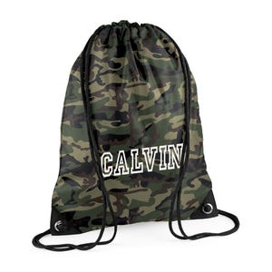 May include: A drawstring backpack with a camouflage pattern in shades of green, brown, and black. The word "CALVIN" is printed in white block letters across the front. The bag has black drawstrings and metal eyelets.