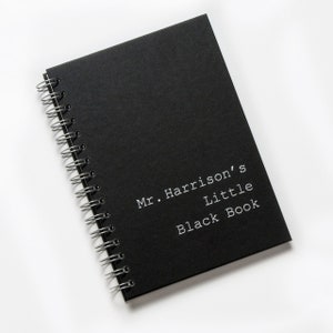 May include: A black spiral bound notebook with the text "Mr. Harrison's Little Black Book" printed in white on the cover.