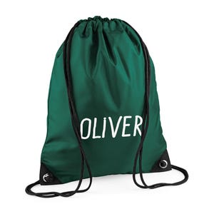 May include: A dark green drawstring backpack with the name "OLIVER" printed in white. The bag has black drawstrings and reinforced corners. This bag is suitable for carrying books, sports gear, or other personal items.