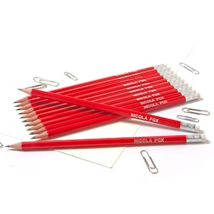 May include: A pack of 12 red pencils with white eraser tips. Each pencil is labeled with the name "NICOLA FOX" in white lettering.