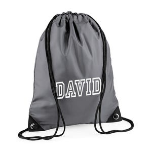 May include: Gray drawstring backpack with the name "DAVID" printed in white block letters. The bag has black drawstrings and reinforced corners. This personalized bag is suitable for carrying sports gear or everyday items.