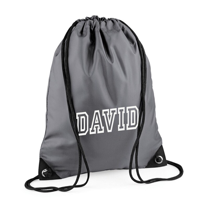 May include: Gray drawstring backpack with the name "DAVID" printed in white block letters. The bag has black drawstrings and reinforced corners. This personalized bag is suitable for carrying sports gear or everyday items.