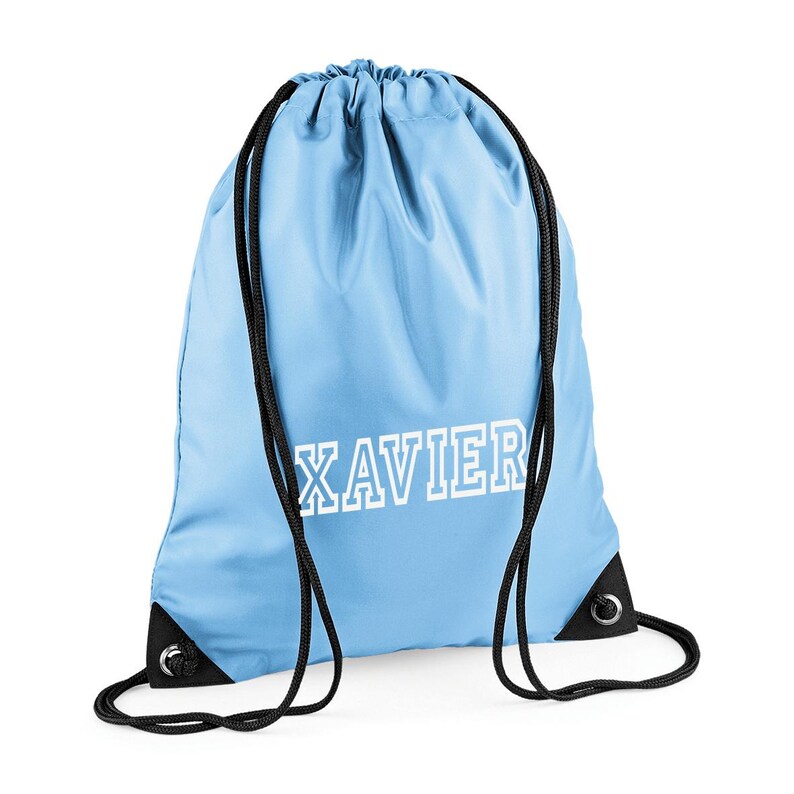 May include: Light blue drawstring backpack with the name "XAVIER" printed in white block letters. The bag has black drawstrings and reinforced corners. This bag is ideal for carrying sports gear or personal items.