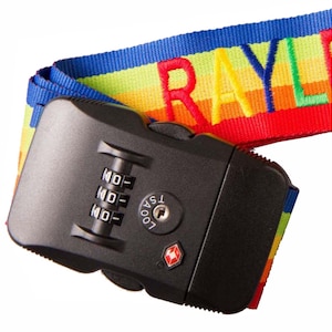 May include: A black luggage strap with a combination lock and a rainbow-colored strap with the word "RAYL" embroidered on it.