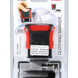 K&ouml;nnte beinhalten: Ein roter und schwarzer Stempel mit Selbsttinte mit dem Text "trodat printy 4911" und "ROBERT NORMAN EXPORT MANAGER 4600 WELS. AUSTRIA". Der Stempel ist in einer durchsichtigen Kunststoff-Klappverpackung verpackt, auf der der Text "CLOTHING MARKER_" aufgedruckt ist.