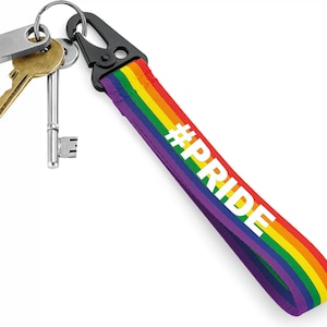 May include: A rainbow-coloured key chain with a black clip and a silver key ring. The key chain has the text "#PRIDE" printed on it in white.