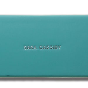 May include: A teal blue box with the text "Sara Cassidy" embossed in silver lettering.