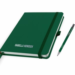 Könnte beinhalten: Ein dunkelgrünes Notizbuch mit einem schwarzen Gummibandverschluss und einem silbernen Stift. Das Notizbuch trägt den Namen "ISABELLA HOWDEN" auf dem Einband.