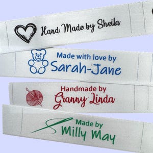 May include: A collection of white fabric labels featuring text and illustrations. The labels display phrases such as "Hand Made by Sheila", "Made with love by Sarah-Jane", "Handmade by Granny Linda", and "Made by Milly May". Each label has a unique design.