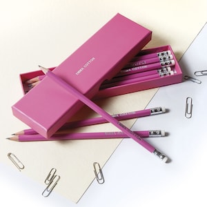 May include: A pink box filled with pink pencils with the text "Emma Cotton" printed on them.