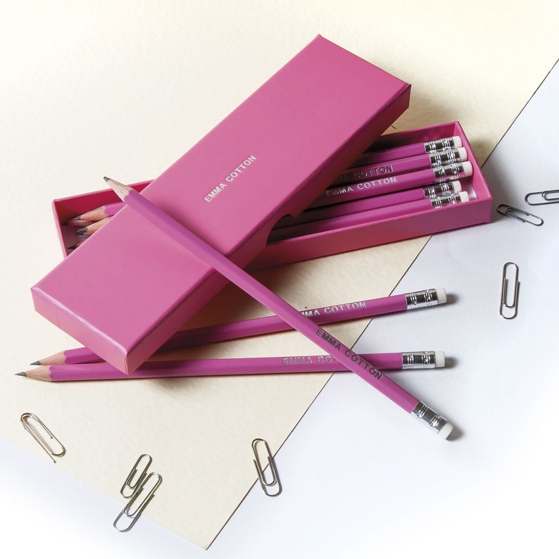 May include: A pink box filled with pink pencils with the text "Emma Cotton" printed on them.
