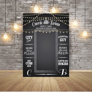May include: A black chalkboard sign with white chalk writing. The sign has a wedding theme with the names "Carrie and Brian" and the date "May 7, 2016". The sign also has a variety of fun phrases like "City Gal", "Country Guy", "More Wine Please", "Funky Buddha Beer", "Go Cubs Go", and "Let's Go Hokies".