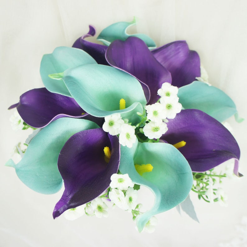 May include: A bouquet of artificial calla lilies in shades of teal and purple, accented with small white flowers.