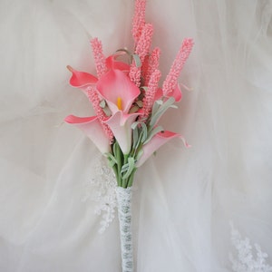 May include: A pink and white bridal bouquet featuring calla lilies and pink flowers, wrapped in white lace.