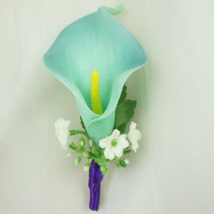 May include: A light blue artificial calla lily boutonniere with white baby's breath and a purple ribbon.