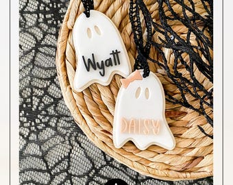 May include: Two white ghost-shaped ornaments with black text that reads "Wyatt" and "Daisy". The "Daisy" ghost has a pink bow. The ornaments are hanging on black string, resting on a woven basket. The text "SVG LASER FILE + COMMERCIAL USE" is at the top.